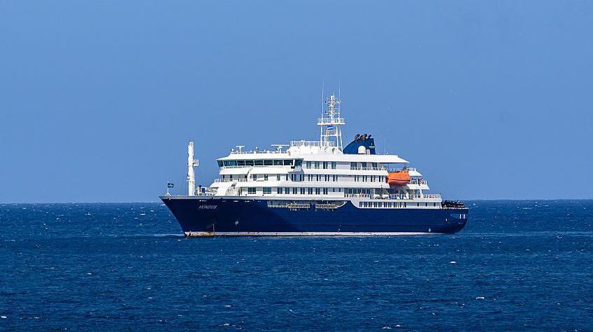 El crucero MV Hondius anclado frente al puerto de Praia, la capital de Cabo Verde, el 3 de mayo de 2026. Es una embarcación de gran tamaño, de color azul y blanco. 