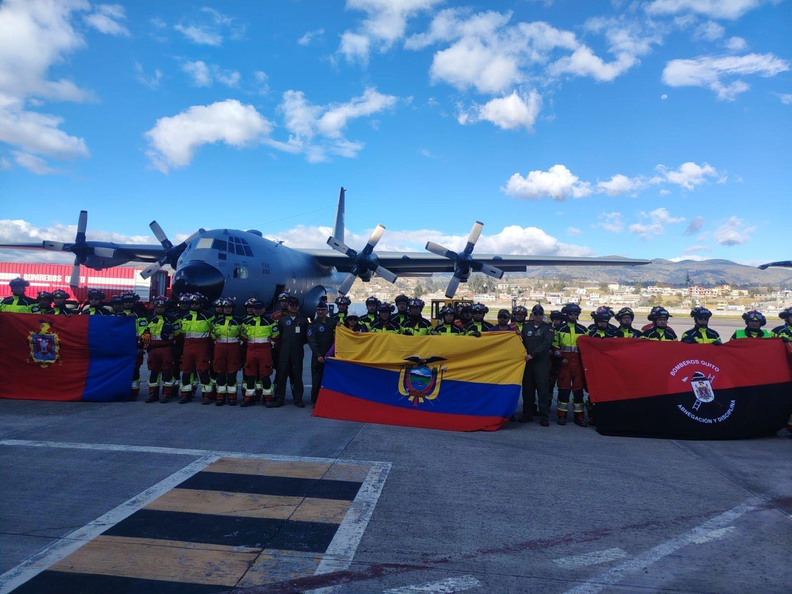 Personal de rescate junto a un avión y una bandera ecuatoriana