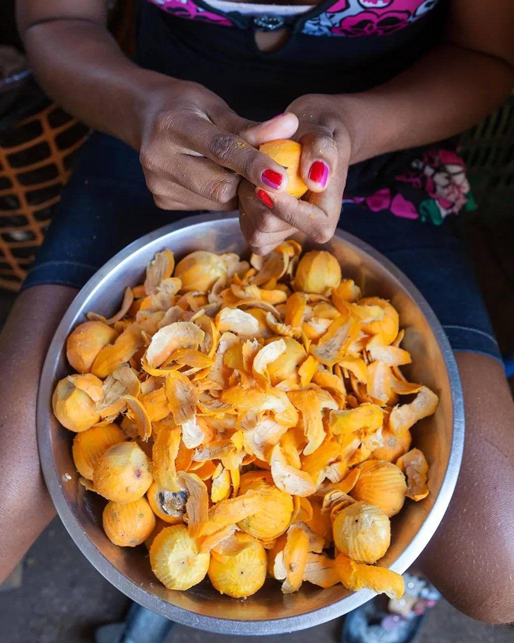 Una mujer pelando frutas de tucumã