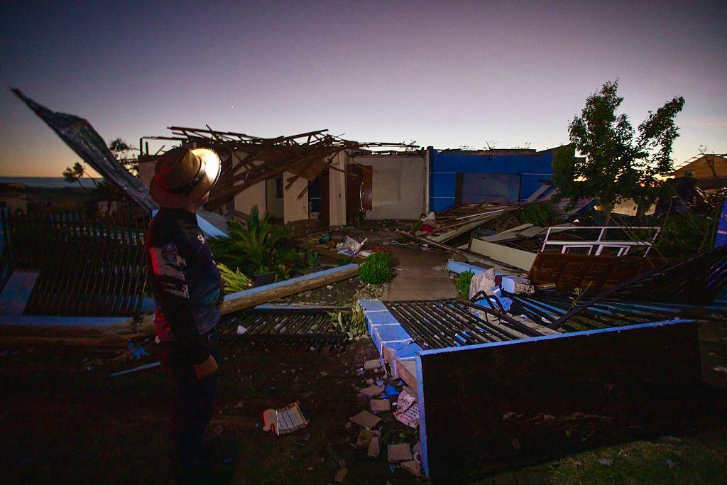 Casas destruídas e um homem olhando para destruição