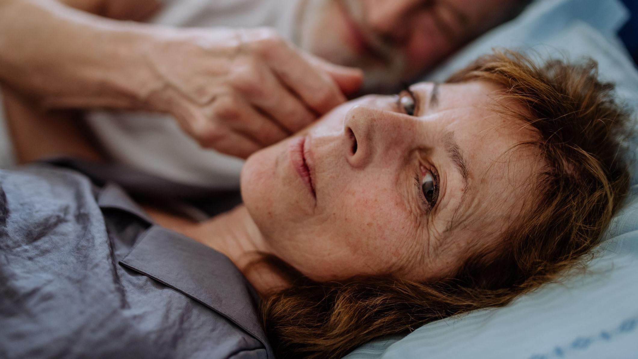Una mujer mayor siendo acariciada en el rostro por un hombre. 