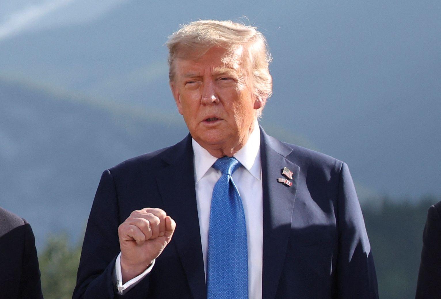 Trump posando para foto, em pé, com feição séria