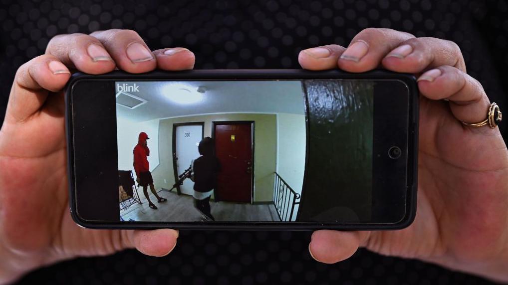 Cindy Romero sostiene su celular con el video de vigilancia que publicó, que supuestamente muestra a miembros armados de la pandilla Tren de Aragua en su antiguo edificio de apartamentos en Aurora, Colorado, el 28 de octubre de 2024.