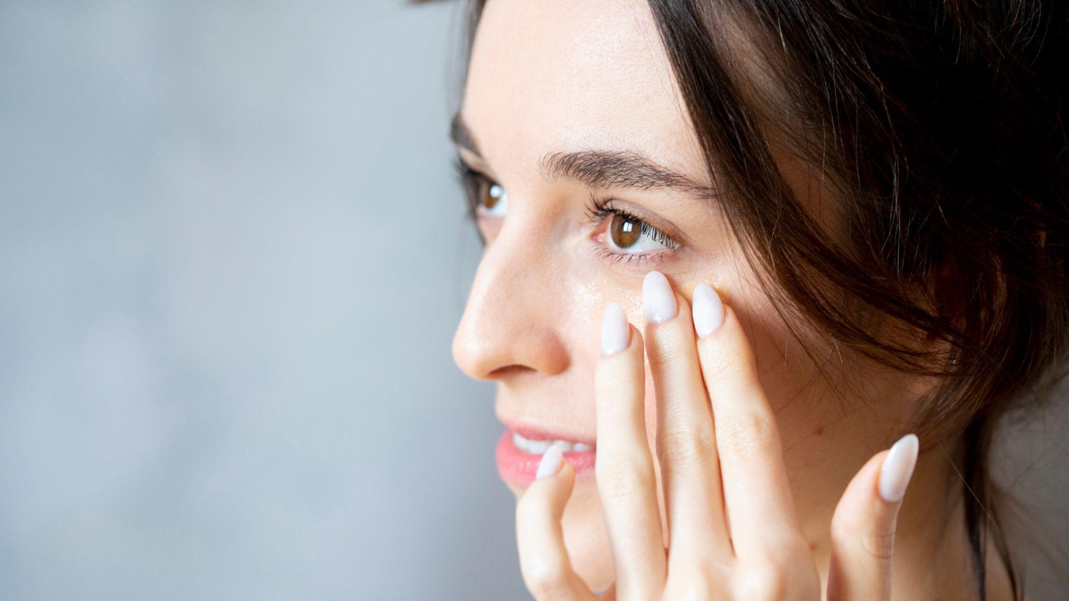 Mulher aplicando creme na regi&atilde;o dos olhos
