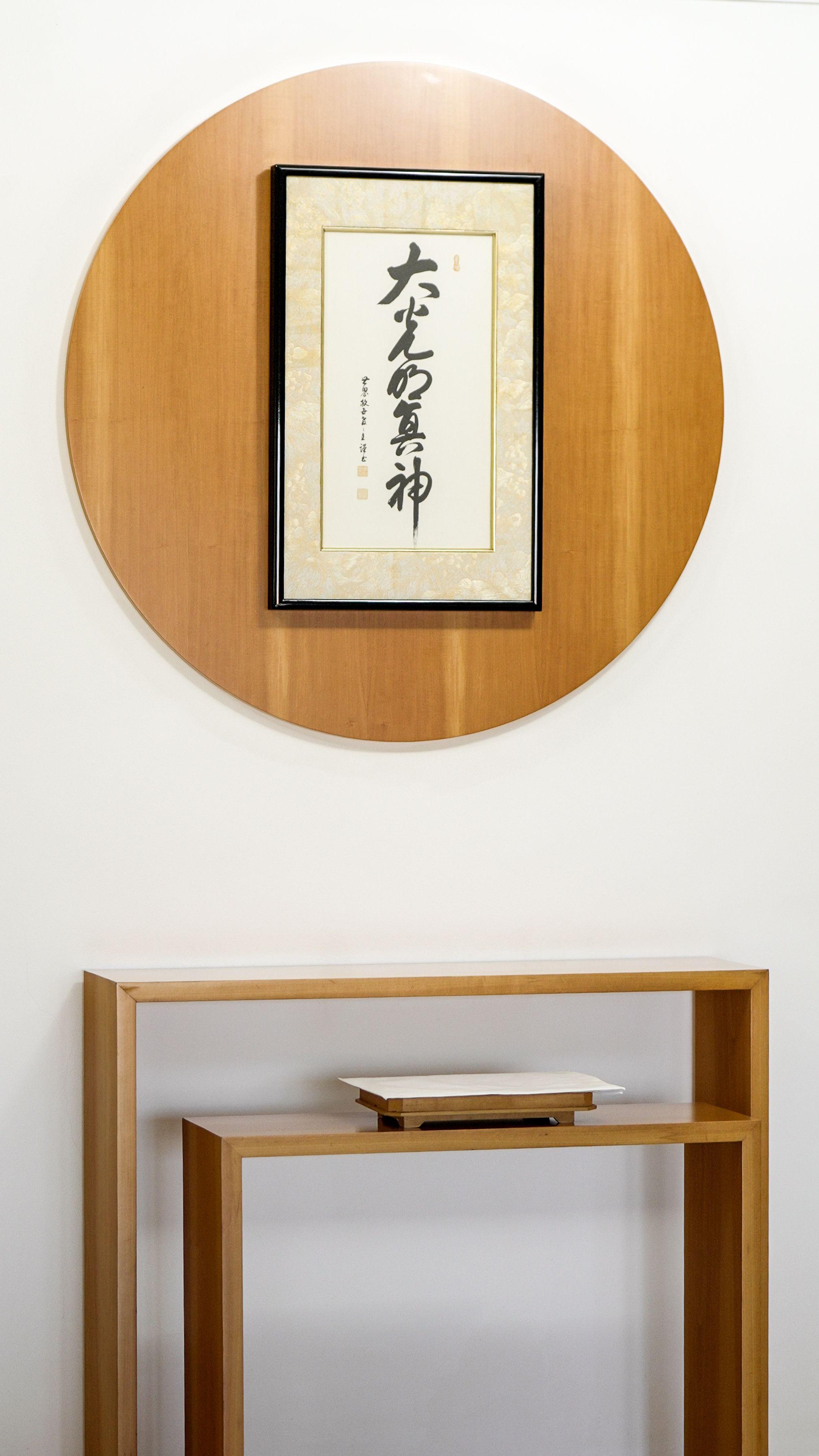Foto de um quadro com ideogramas japoneses e uma mesa de madeira. 