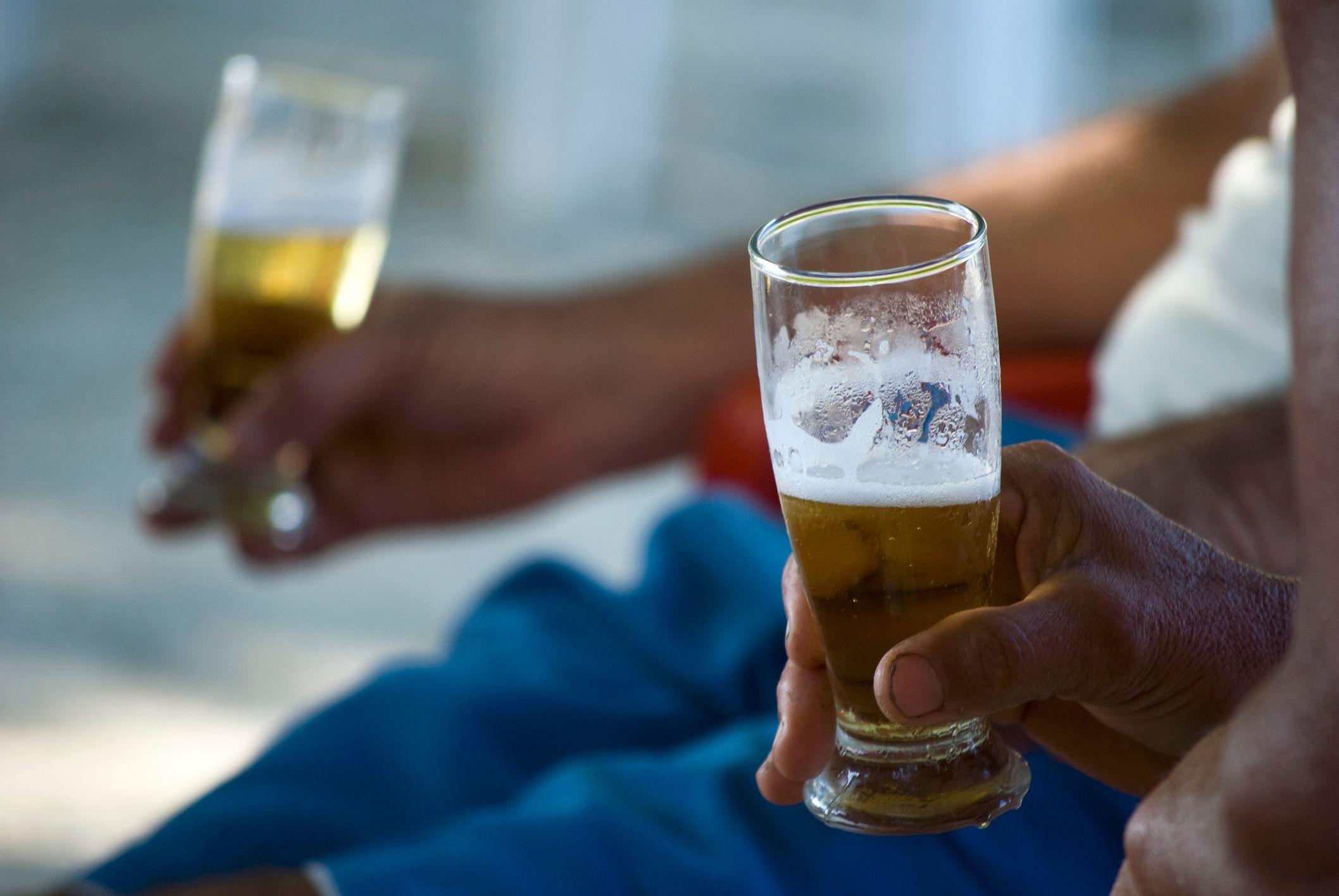 Duas m&atilde;os segurando ta&ccedil;as de chope