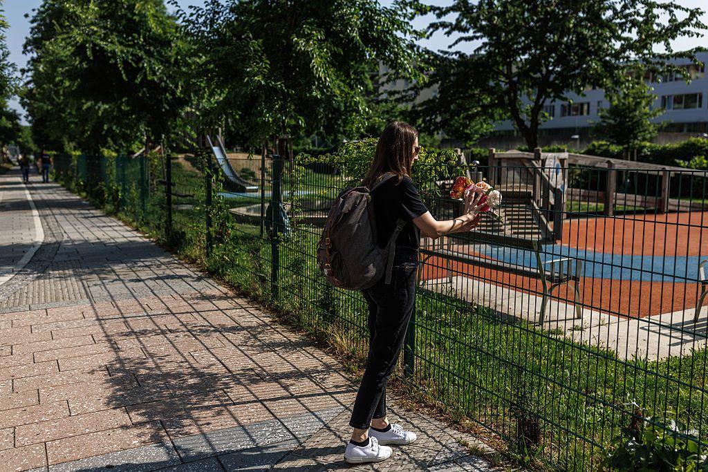 Mujer depositando flores en una valla