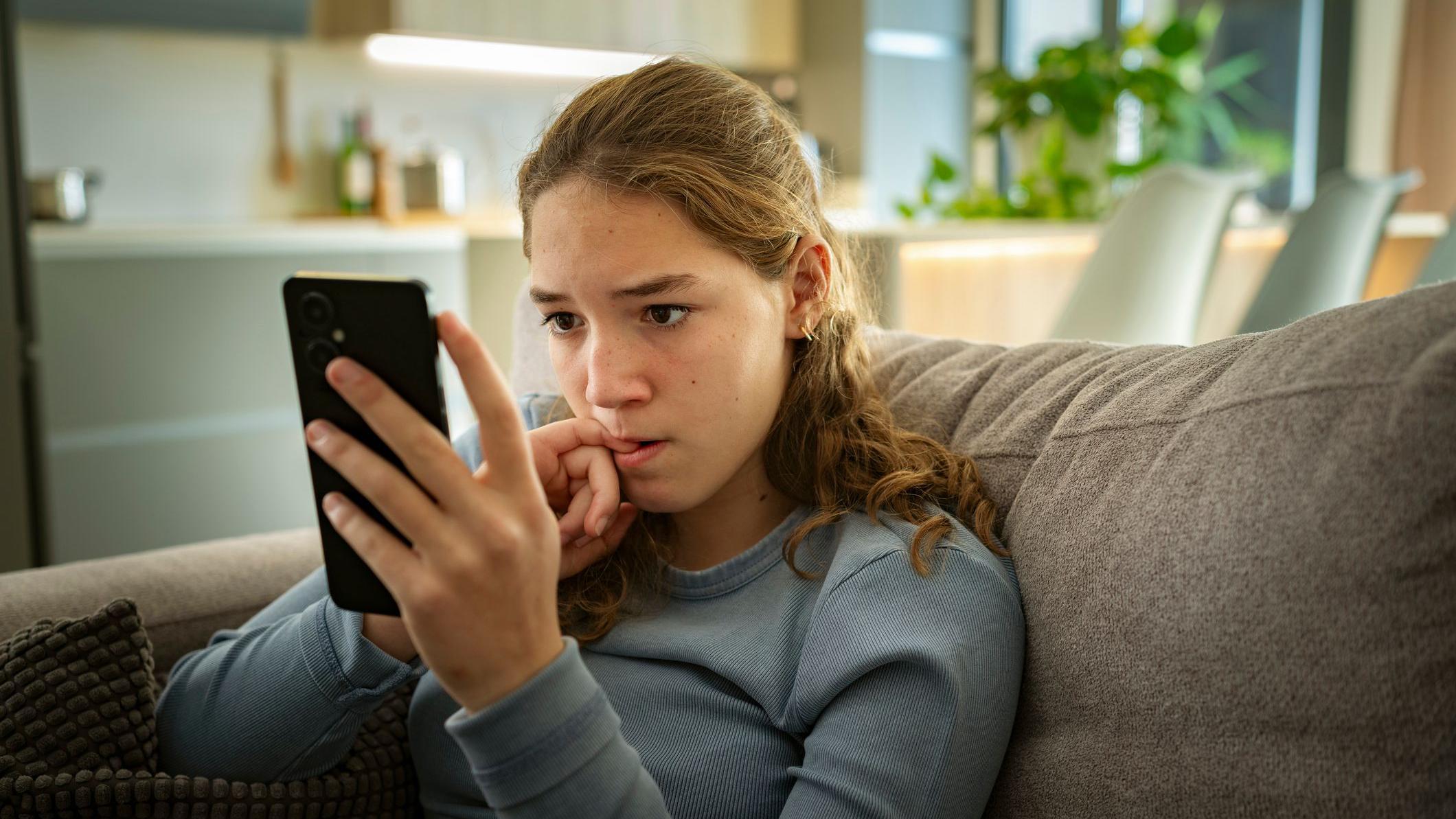 Tinejdžerka sedi i gleda u telefon
