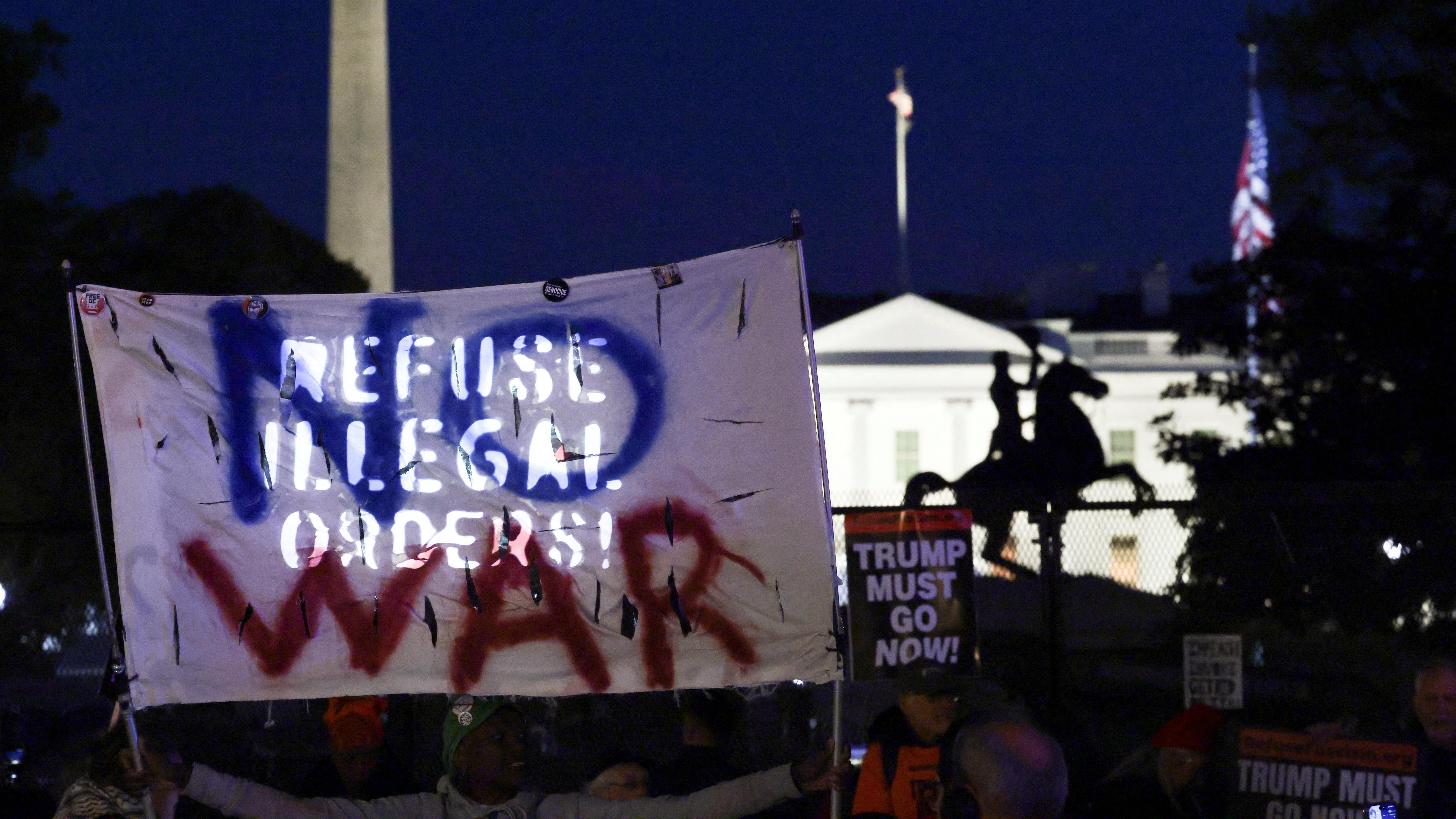 美國華盛頓白宮外反戰群眾舉起呼籲美軍「違抗非法命令」的標語布條，旁邊豎立著「特朗普必須下台」標語牌（7/4/2026）