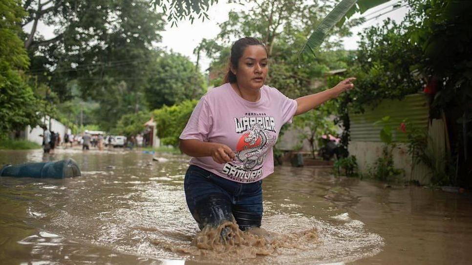 Mujer camina con el auga por las rodillas en Poza Rica, México