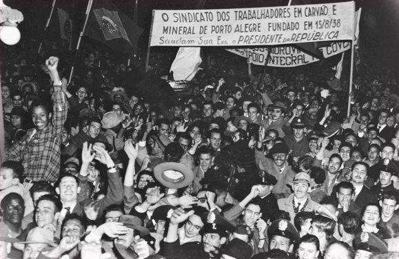 Pessoas aglomeradas com cartazes em foto em preto e branco