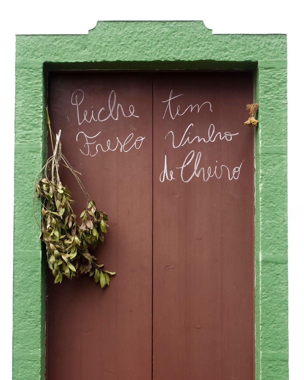 Una puerta marrón rodeada de verde con palabras escritas en portugués