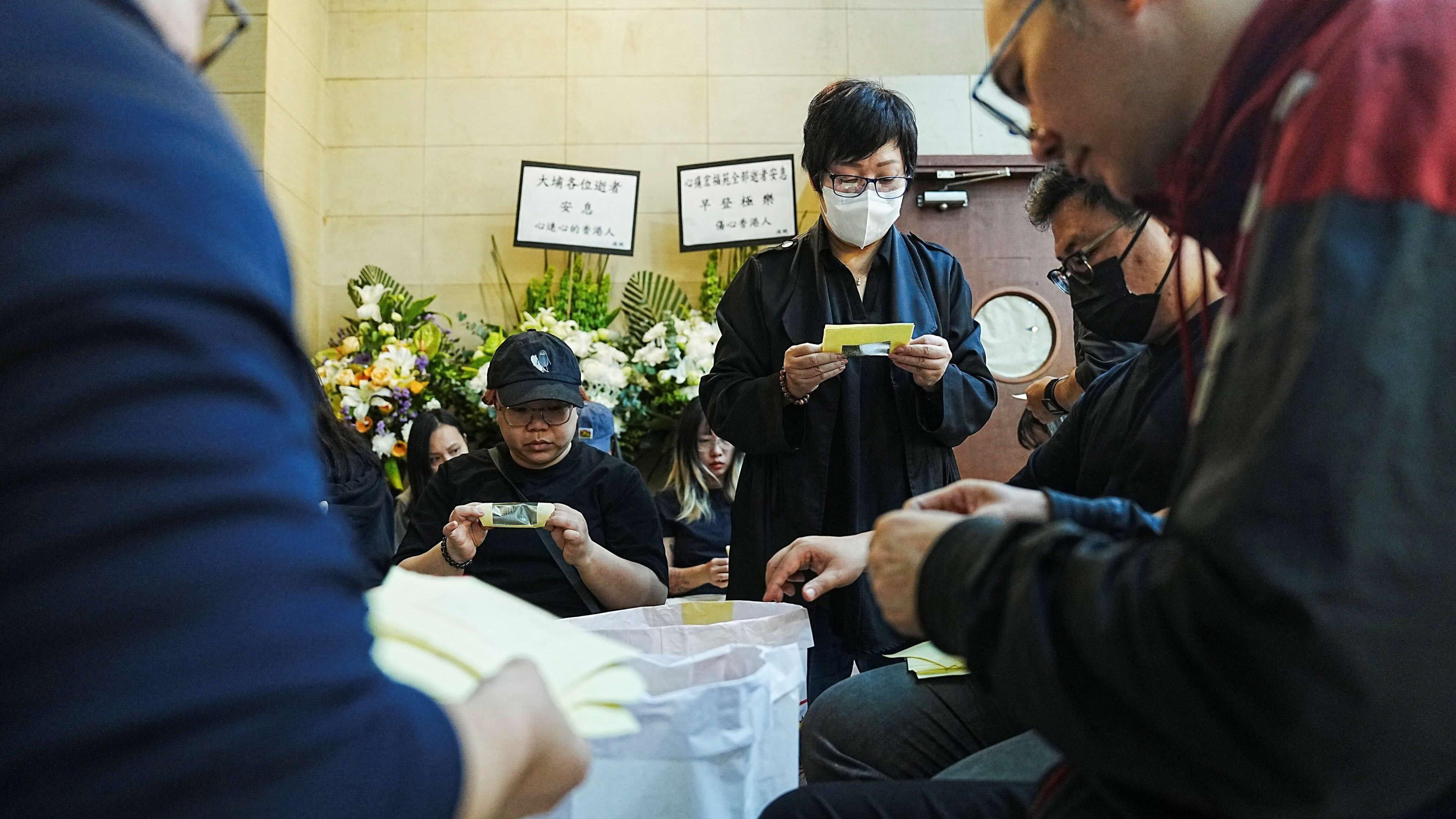 九龍殯儀館，人們在摺元寶，悼念大埔宏福苑遇難者。