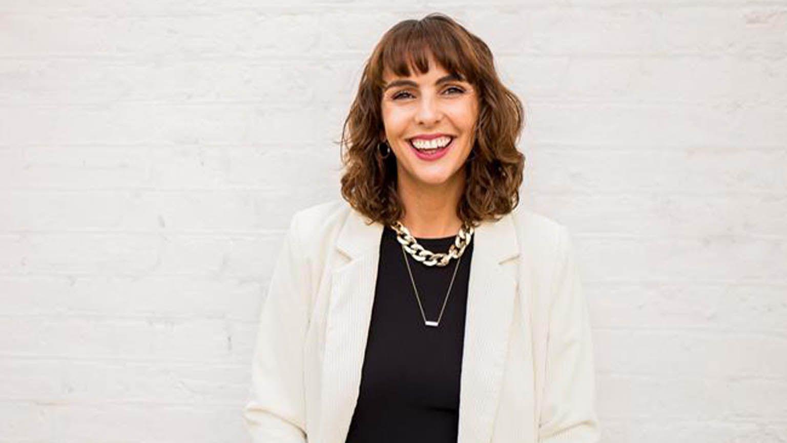 身穿白色西服外套與黑色上衣的維琪·派維特，她的照片被置於相框中