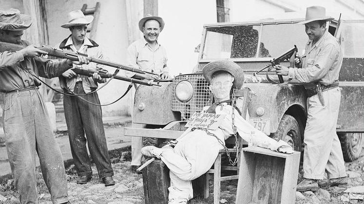 一張黑白照片中，前瓜地馬拉總統哈科波·阿本斯的肖像人偶被靠在一輛吉普車上，數名戴帽男子以槍指向它。人偶胸前掛著一塊寫著西班牙語「我要回到俄羅斯」的牌子