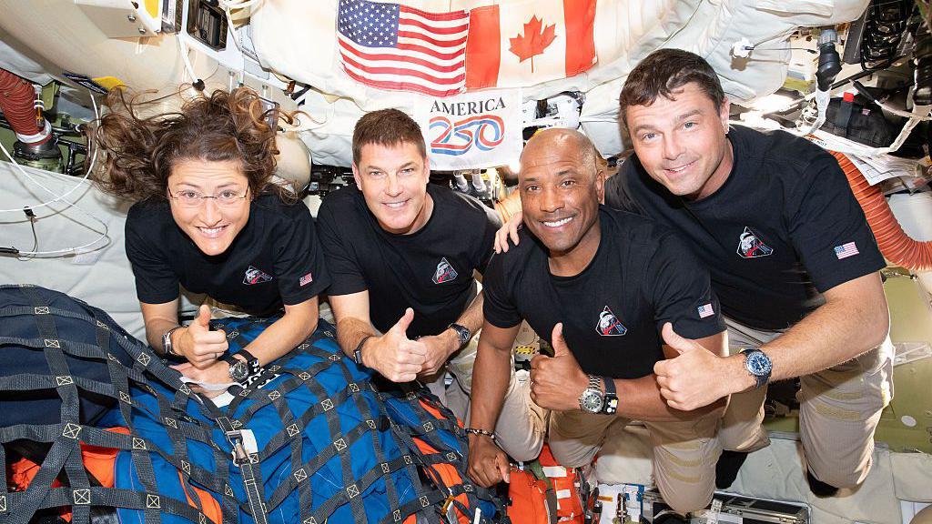 Foto dos quatro tripulantes da Artemis 2, com o polegar para cima, flutuando no interior da espa&ccedil;onave