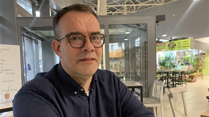 Muškarac sa naočalama u tamno plavoj košulji gleda u kameru, portretna fotografija