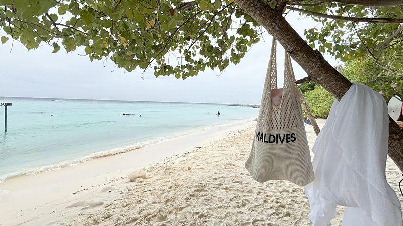 Praia das Maldivas, com uma sacola com a inscrição 'Maldivas', em inglês, pendurada em uma árvore