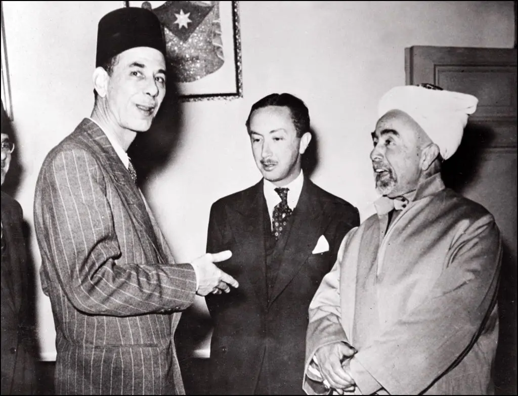 الملك عبد الله (يمين) ملك شرق الأردن (الأردن لاحقاً) يتحدث إلى عبد الرحمن عزام (يسار)، الأمين العام لجامعة الدول العربية، وعبد الإله بن علي، ولي عهد العراق (في المنتصف) وذلك في 13 مايو/أيارعام 1948 قبيل إعلان قيام دولة إسرائيل واندلاع الحرب العربية الإسرائيلية الأولى.
