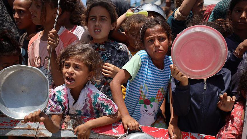 Niños palestinos esperan que les den alimentos.