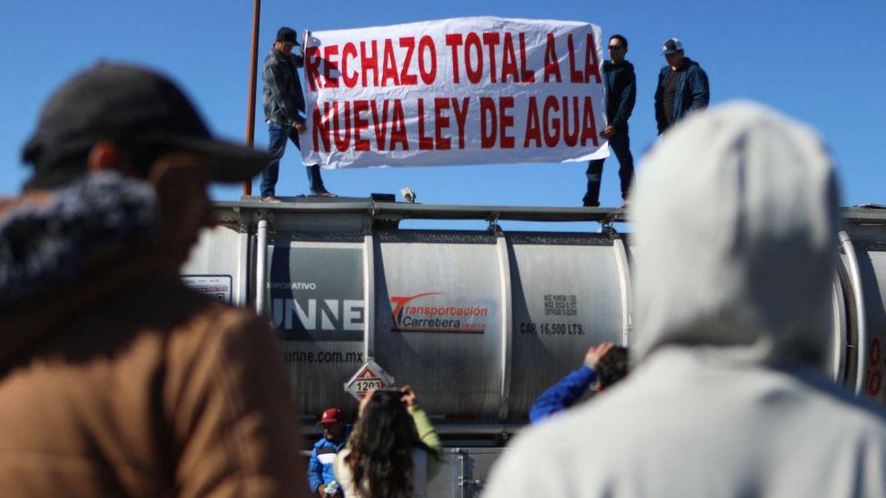Unas personas sostienen una pancarta que dice Rechazo total a la nueva ley de Agua, mientras otras personas observan