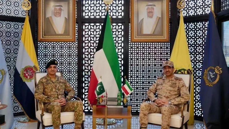 مسؤلان بارزان من الكويت وباكستان بلباس عسكري وخلفهما علما بلادهما.
