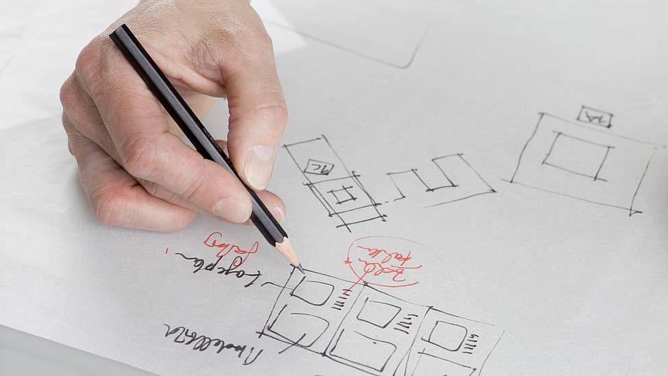 Una mano con un lápiz dibujando un gráfico en un papel