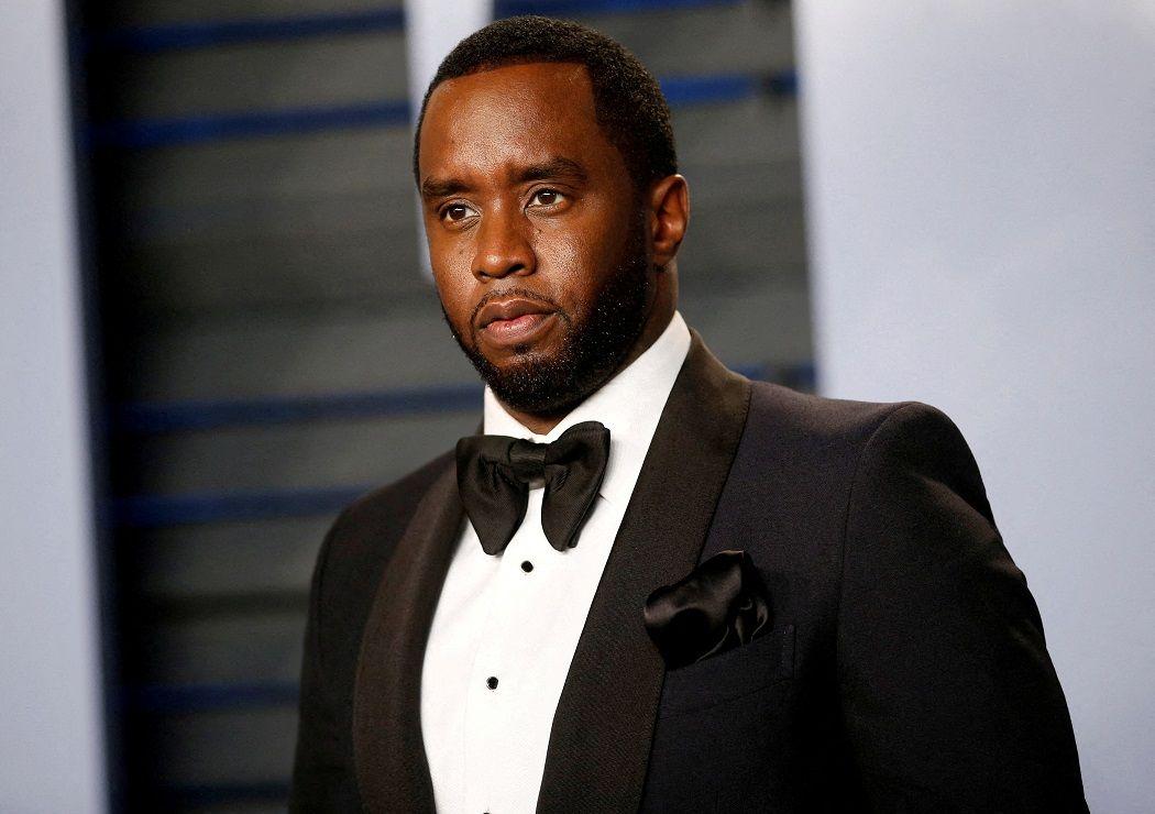 Diddy posando com roupa de gala, em pé em evento; ele tem olhar sério