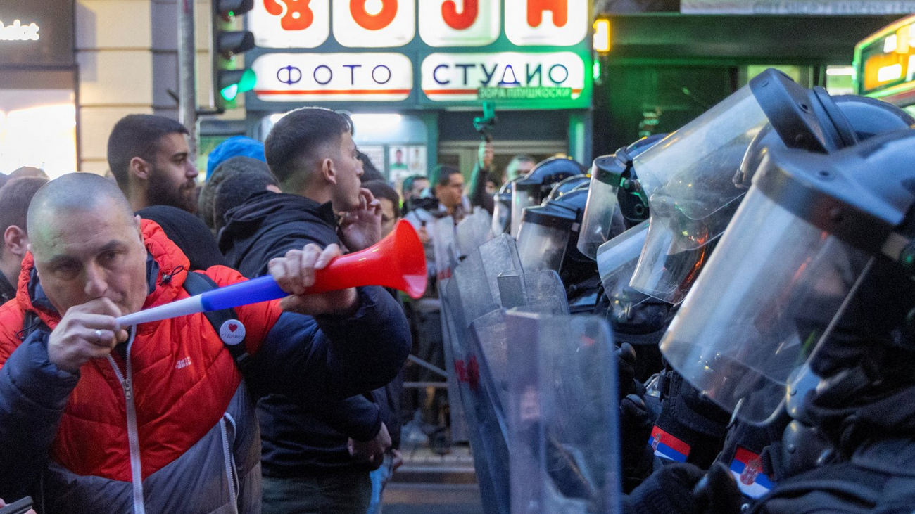 Muškarac duva u vuvuzelu ispred kordona policije 