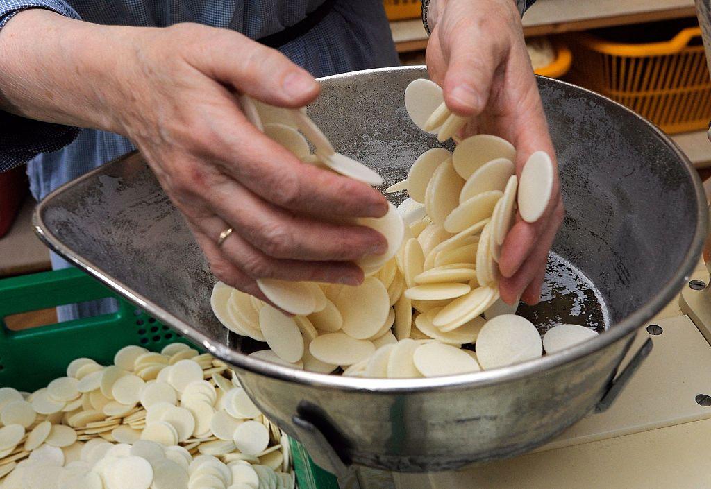 Una monja colocando en un recipiente unas hostias recién hechas.