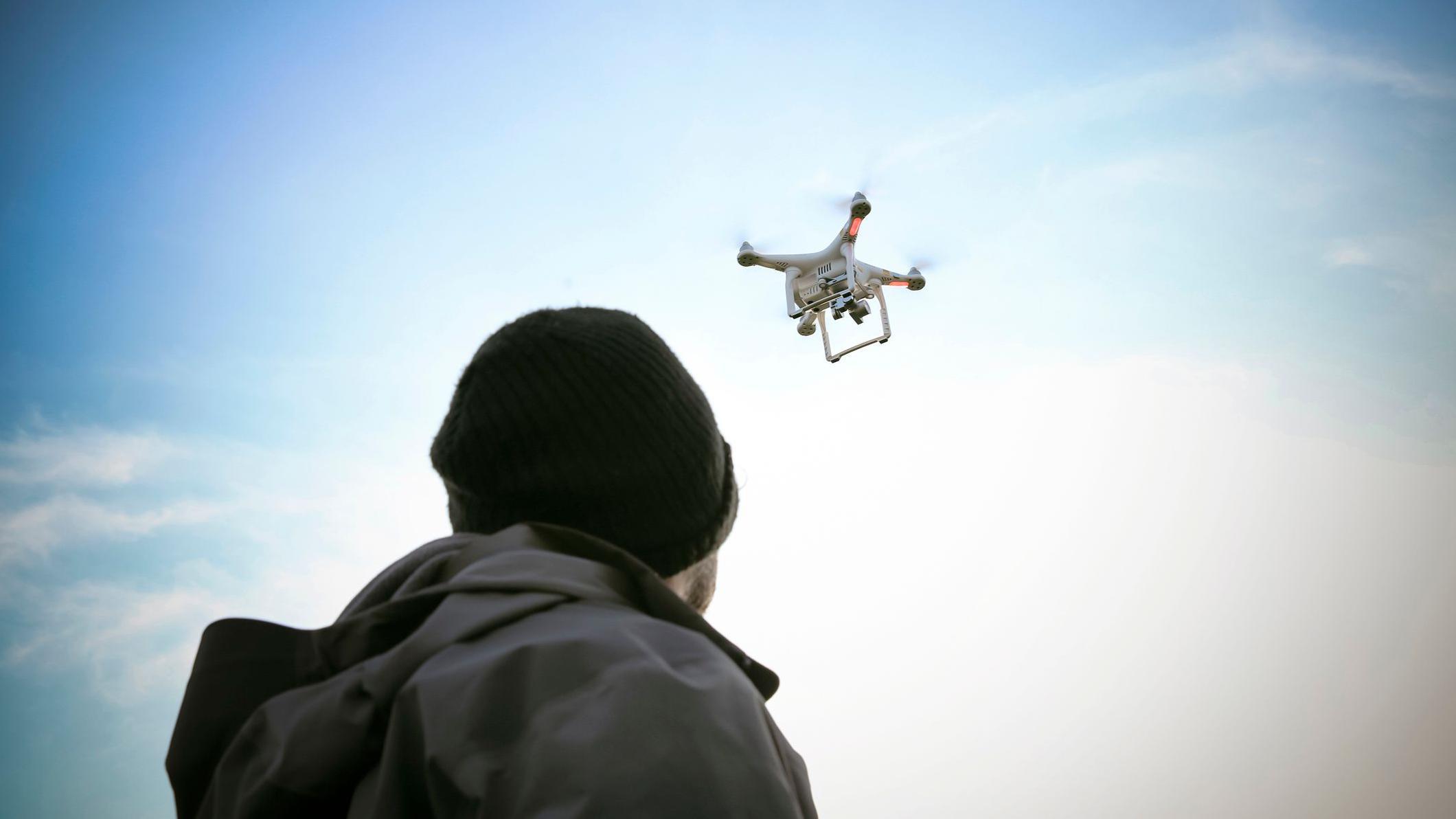 شخص ينظر إلى مسيّرة تحلق فوقه - صورة توضيحية