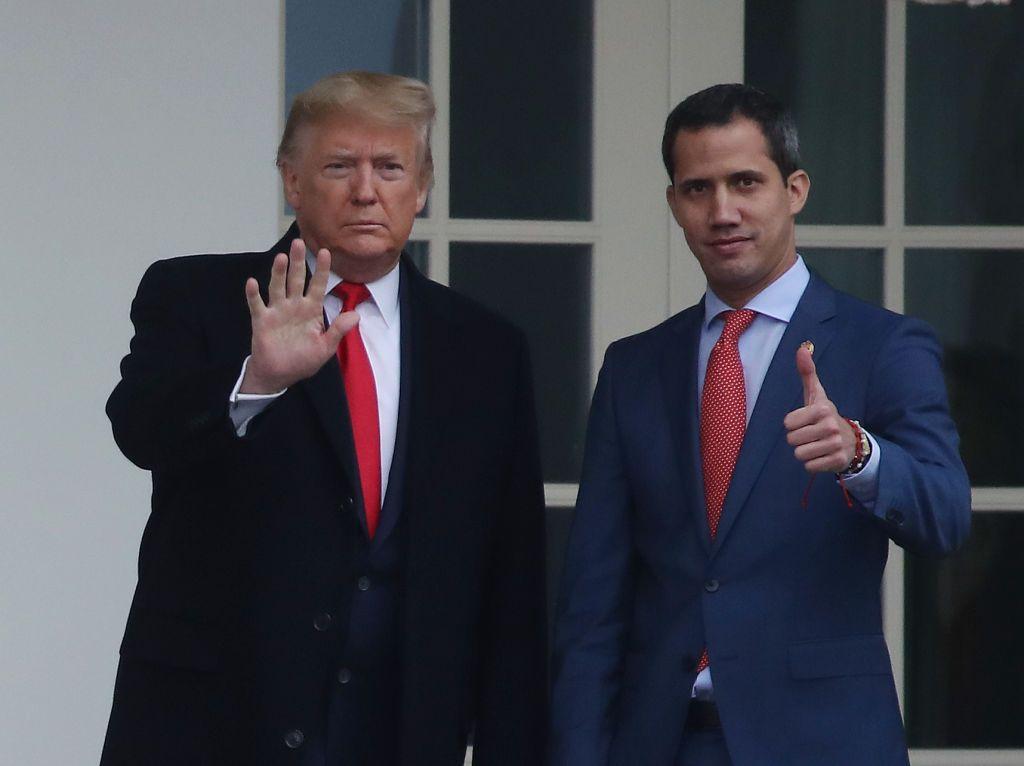 Donald Trump y Juan Guaidó miran hacia el frente y saludan.