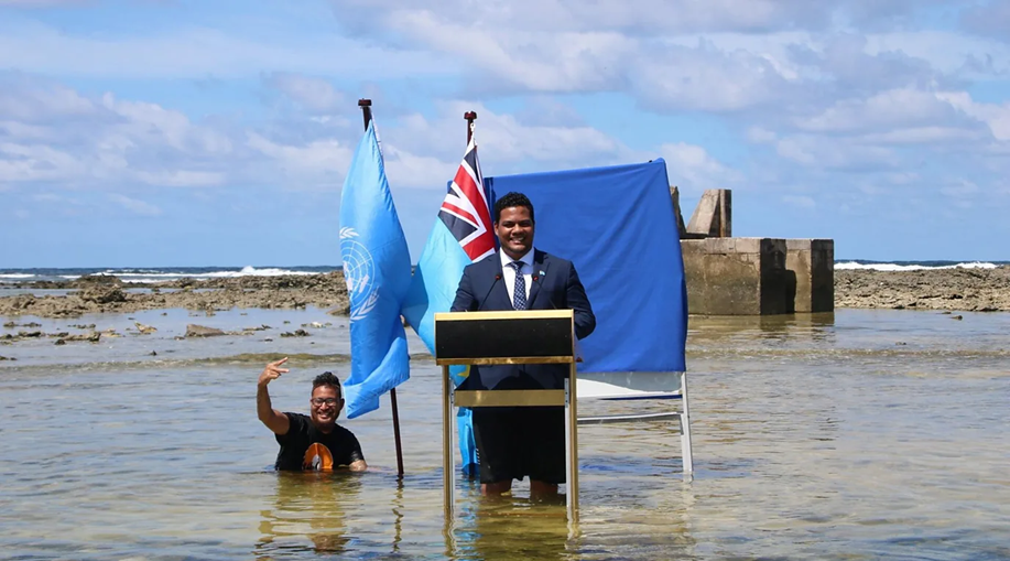 وزير خارجية توفالو سيمون كوفي وهو يقف في البحر حتى ركبتيه أثناء إلقائه خطاباً في عام 2021