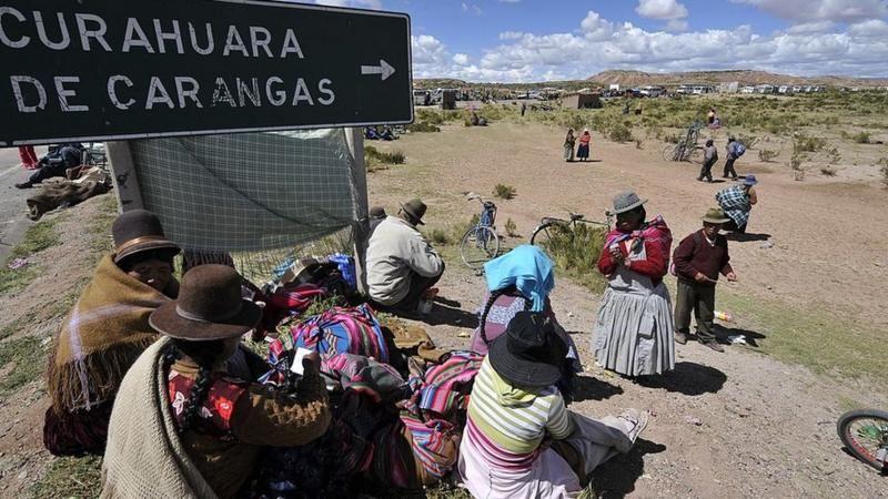 Personas pertenecientes a los aymara caminan por un poblado largo. 