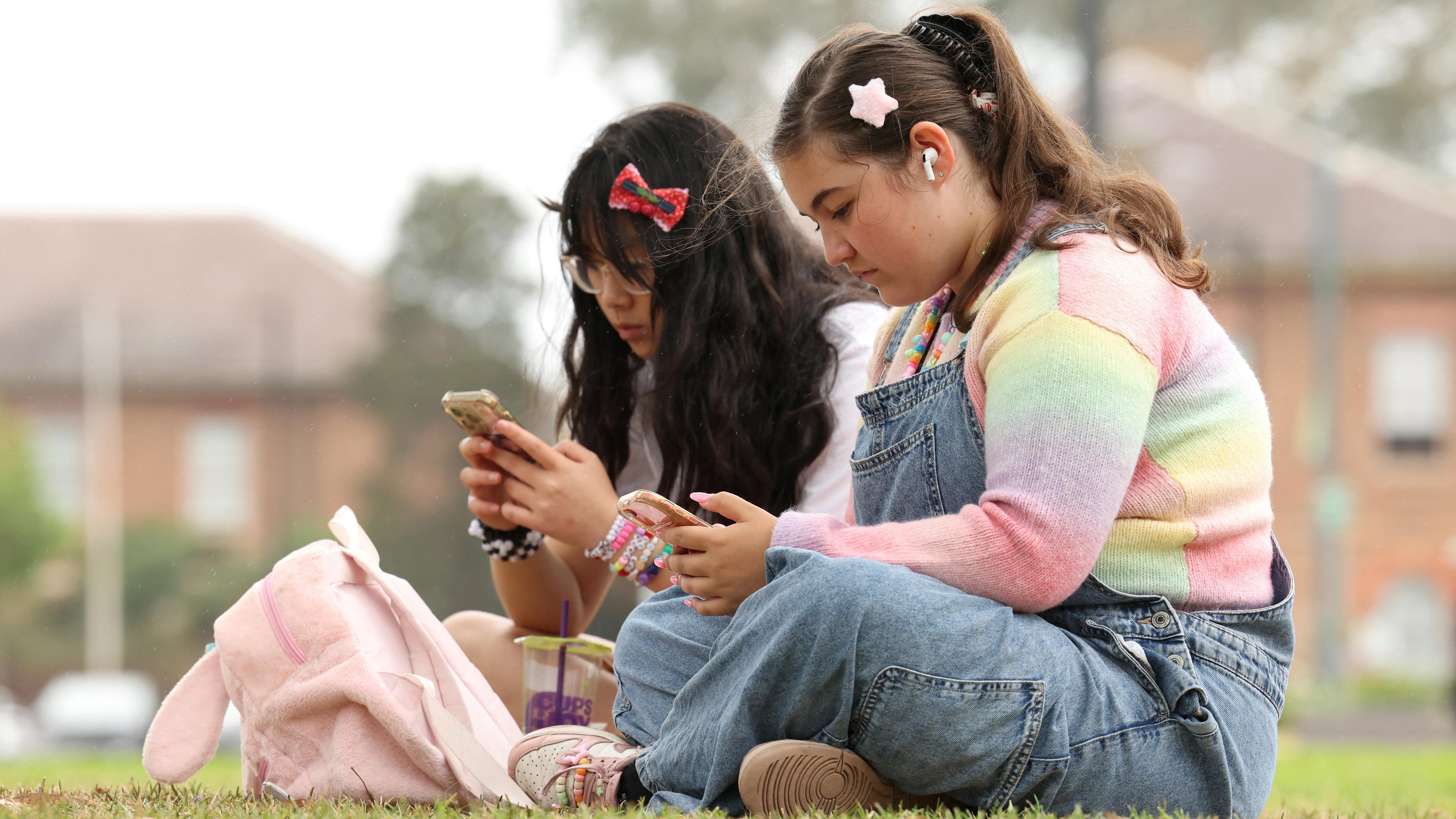 آني وانغ، 14 عاماً، وأيريس تولسون، 15 عاماً، تستخدمان هواتفهما المحمولة، قبل بدء سريان حظر وسائل التواصل الاجتماعي في أستراليا على المستخدمين دون سن 16 عاماً.