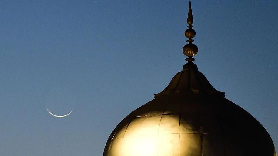 منظر للهلال خلف القبة الذهبية للمسجد الرئيسي في دلهي