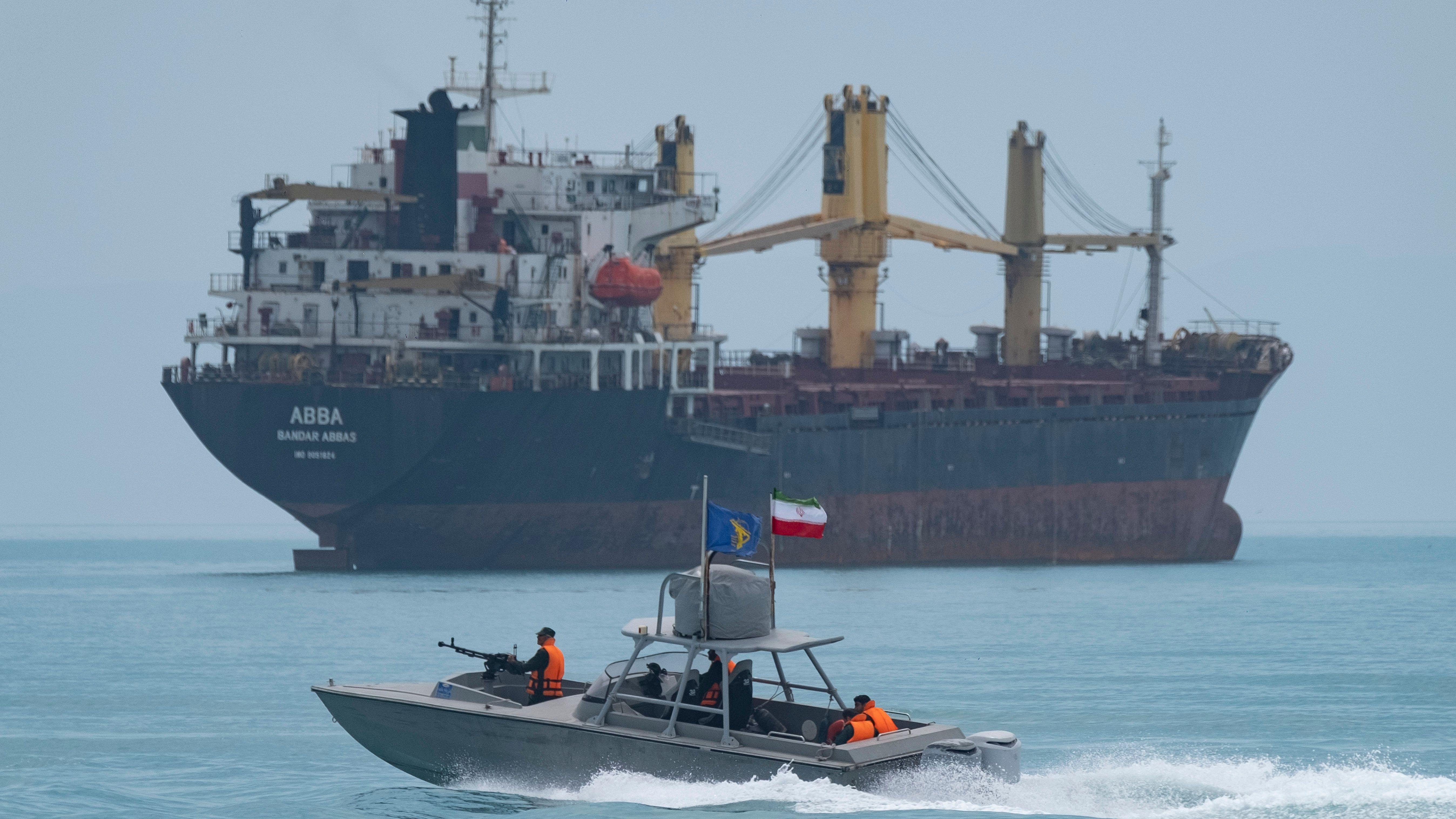 زورق سريع تابع للحرس الثوري الإيراني يبحر على طول الخليج بالقرب من سفينة شحن عامة خلال عرض بحري
