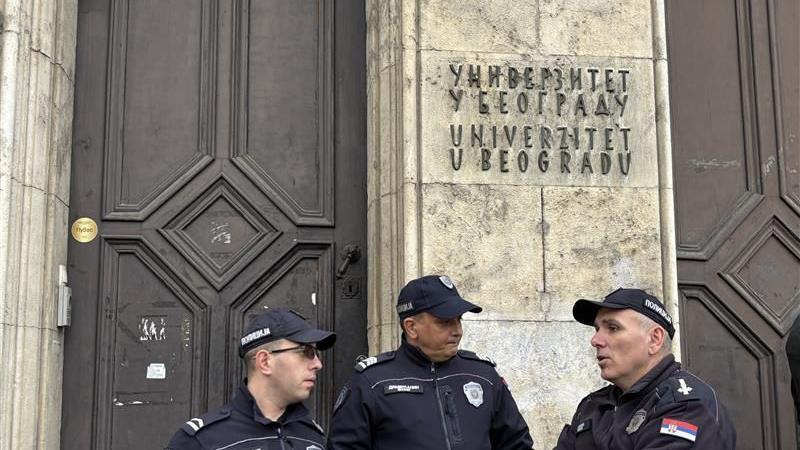 Trojica policajaca stoje u uniformama ispred zgrade rektorata u Beogradu, iznad njih je natpis Univerzitet u Beogradu