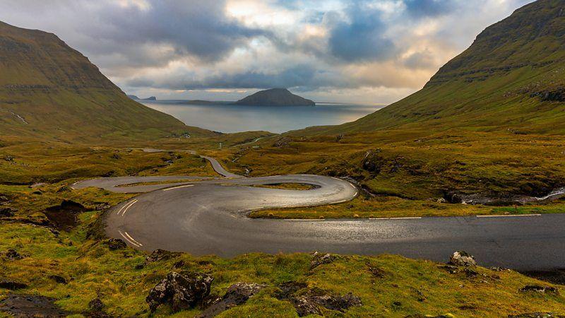 Estrada sinuosa com o mar e uma ilha ao fundo