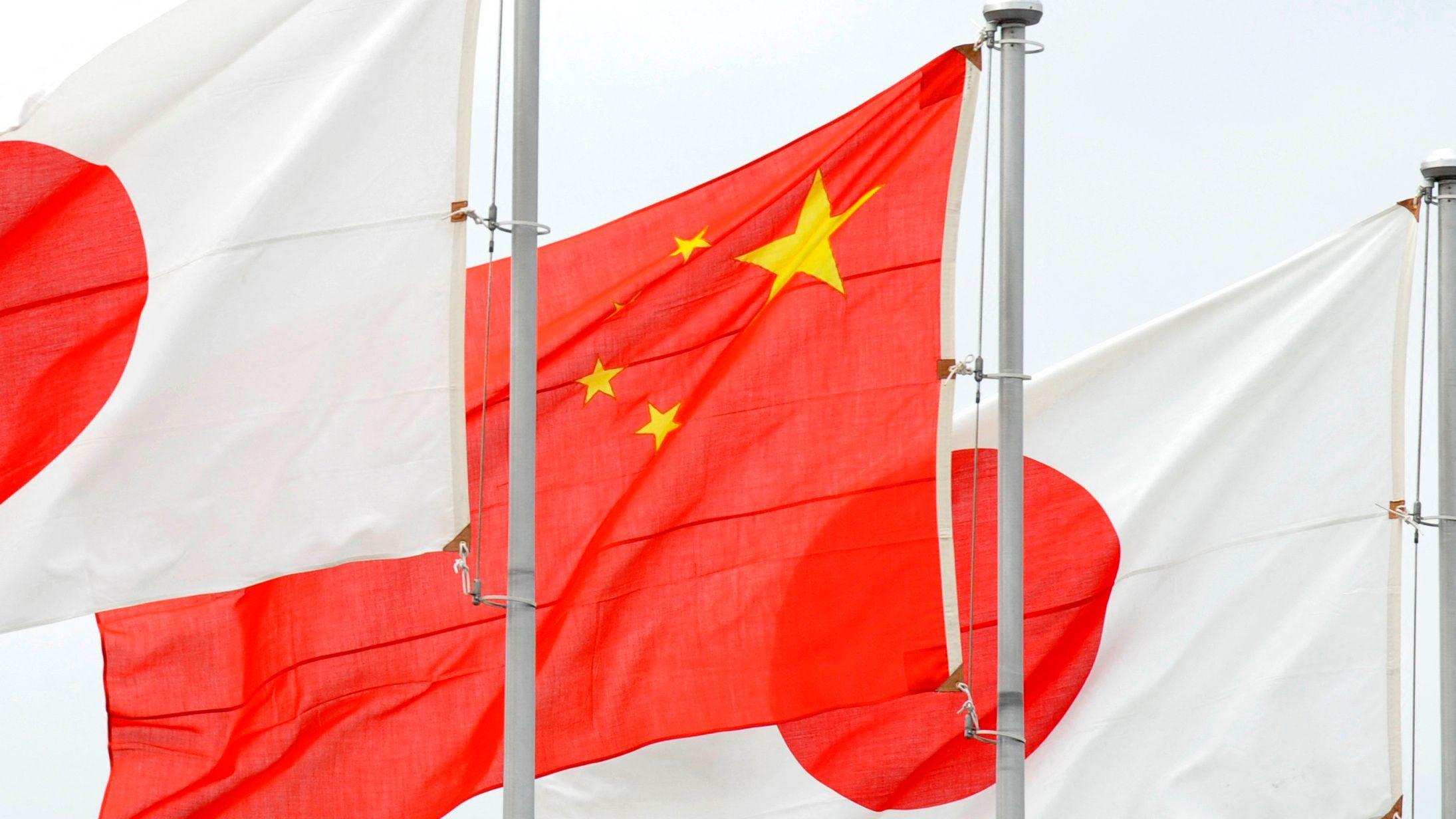 عُرض العلم الصيني (وسط) والعلم الياباني لدى وصول نائب الرئيس الصيني شي جين بينغ إلى مطار هانيدا بطوكيو في 14 ديسمبر/كانون الأول 2009. 