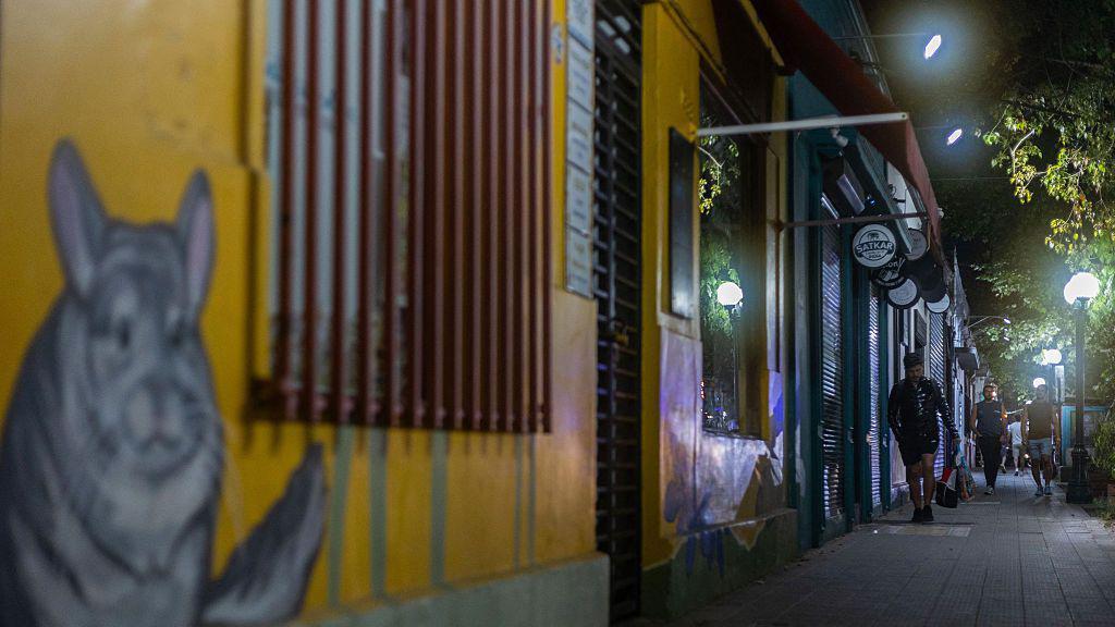 Pessoas caminhando numa calçada à noite