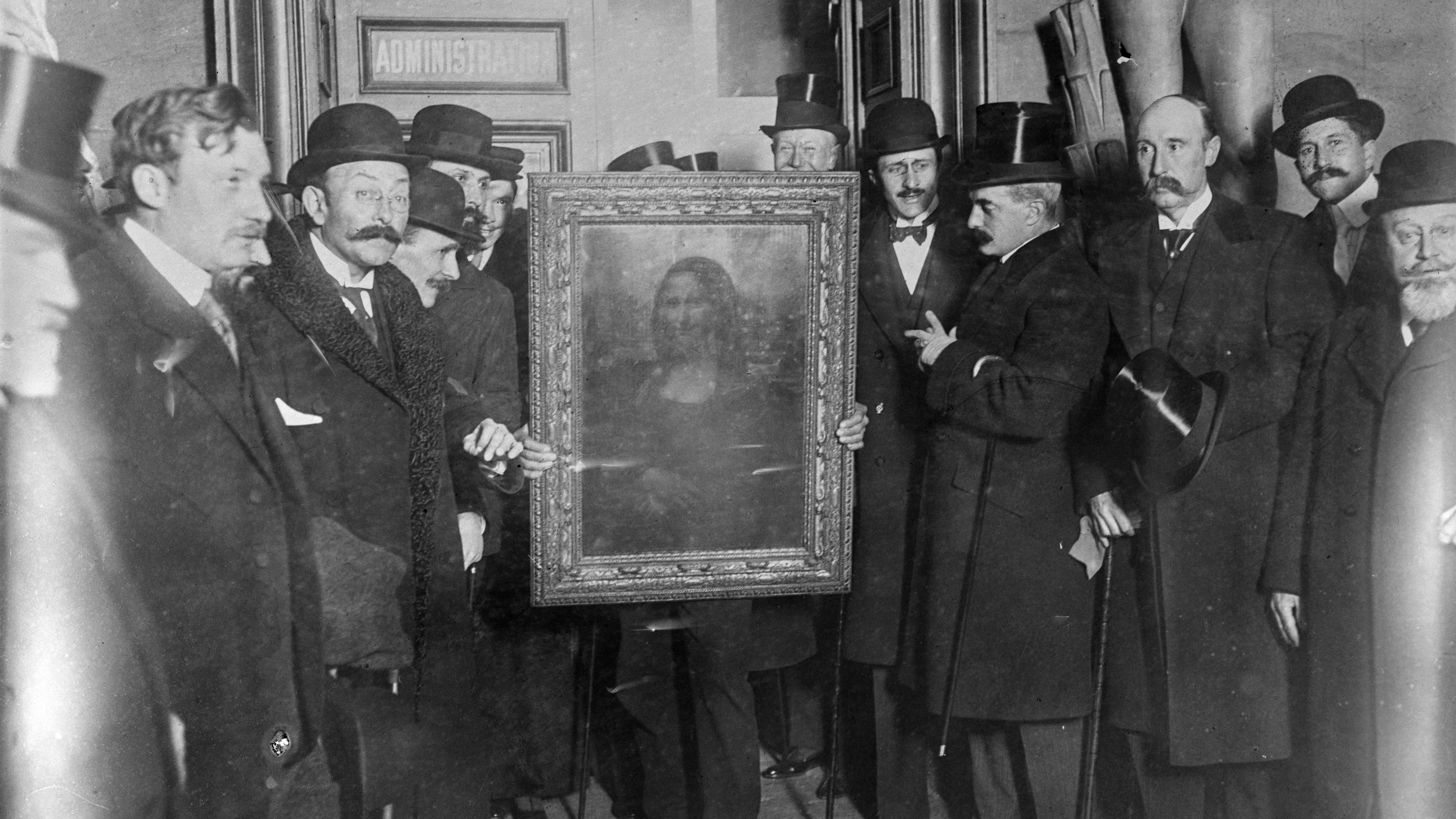 Imagem em preto e branco de 1914, mostrando um grupo de homens de terno, gravata e cartola. No centro, a imagem original da Mona Lisa