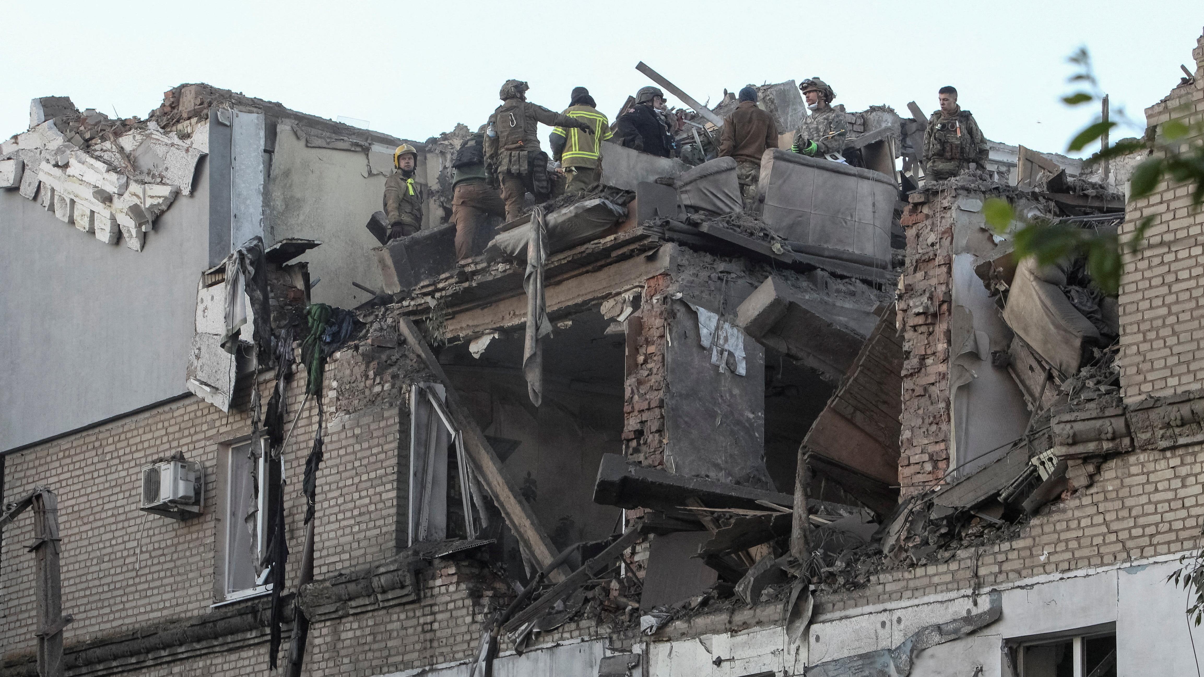 Los bomberos se encuentran en lo alto de un edificio de apartamentos destruido en Dnipro (Ucrania) tras una serie de ataques rusos durante la noche.