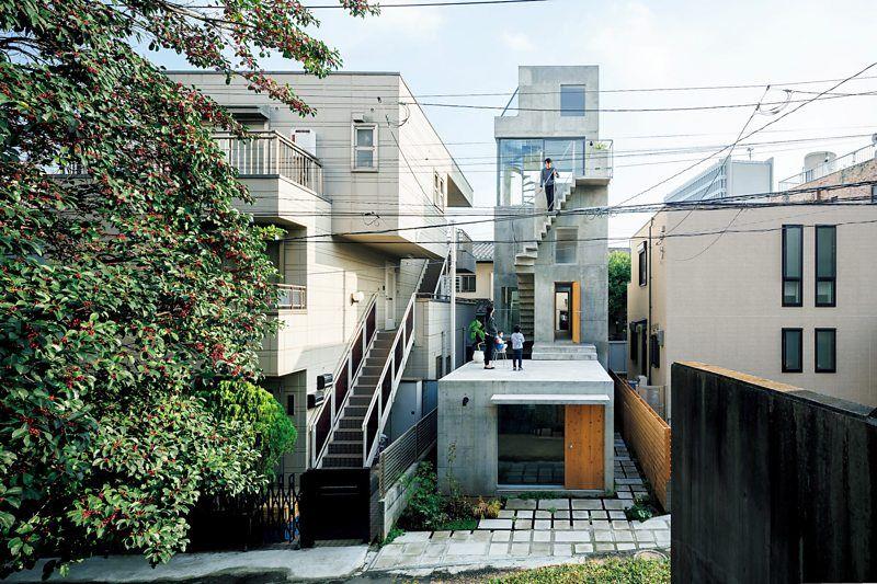Casa com uma torre com escada externa em um terreno minúsculo, ao lado de outras construções no meio da cidade