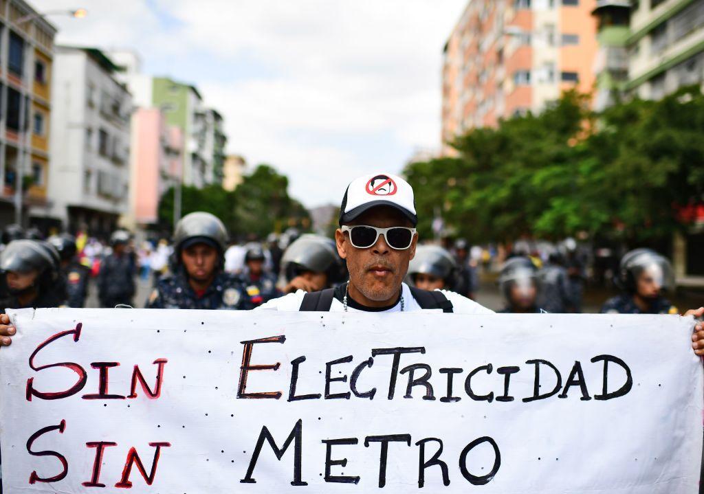 Una persona protesta en Caracas con un cartel que dice: "Sin electricidad, sin metro".