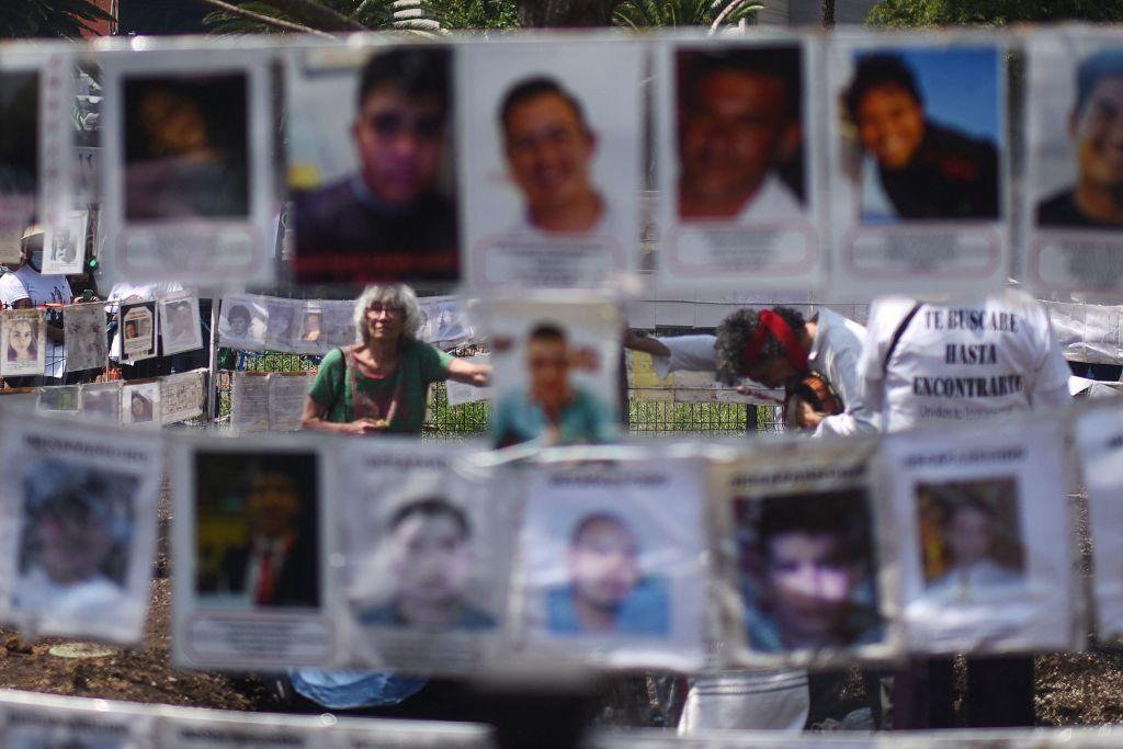 Unos familiares de desaparecidos junto a fotos de ellos en México