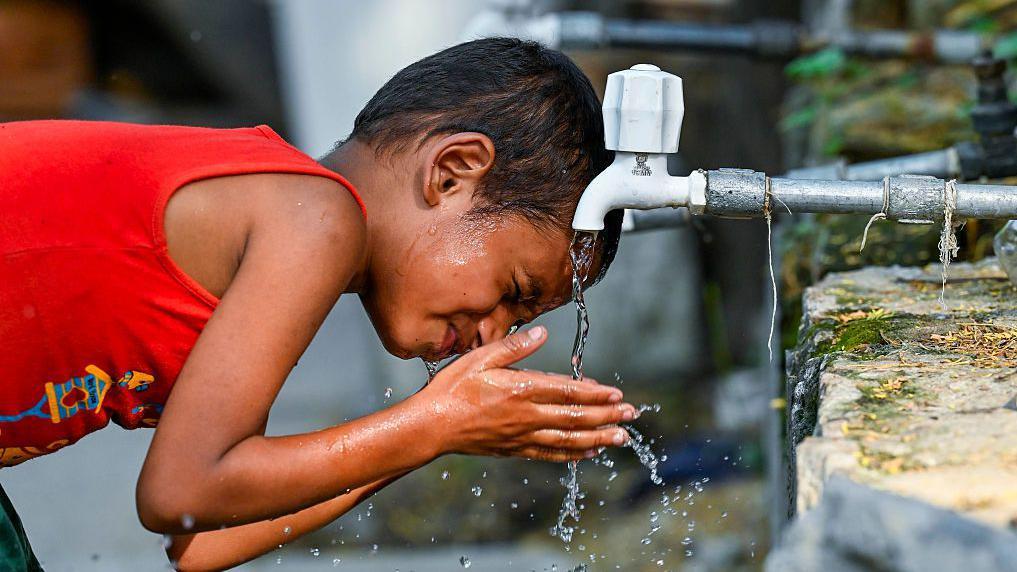 Un niño calma su sed con agua del grifo de un tanque durante una ola de calor abrasadora el 12 de junio de 2025 en Nueva Delhi, India.