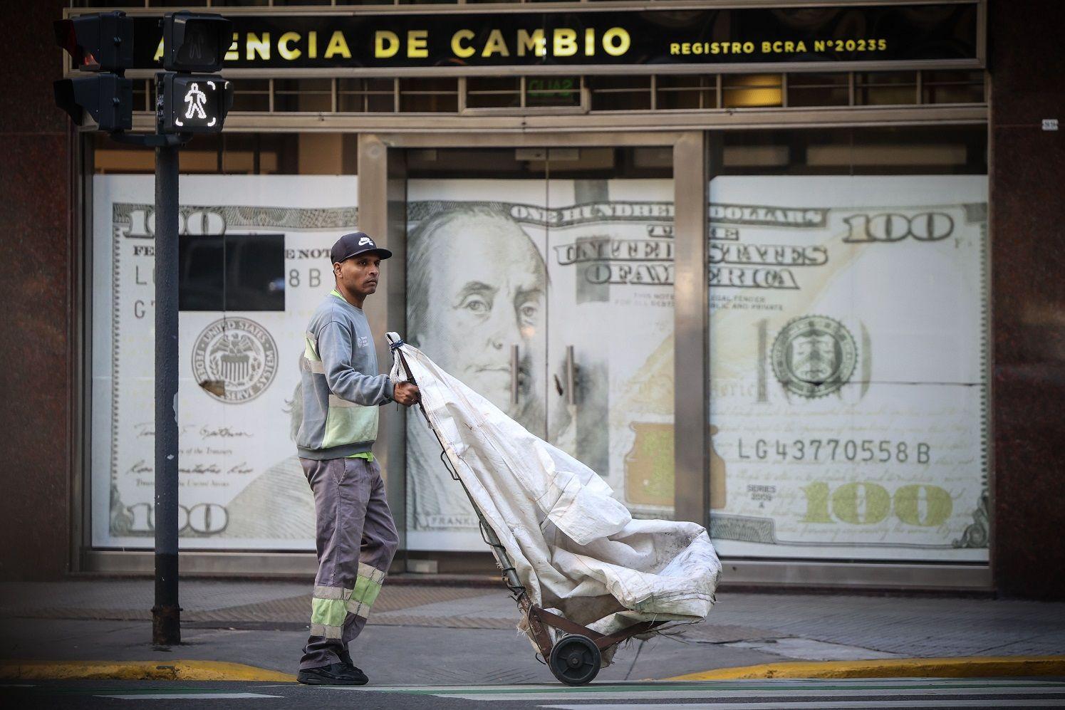 Hombre delante de un afiche de un billete de 100 dólares en Buenos Aires