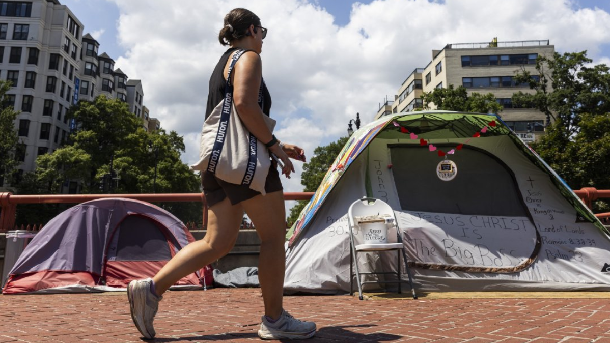 Una peatón pasa junto a carpas de personas sin hogar en Washington Circle, en Washington, DC, EE. UU., el 11 de agosto de 2025. (Foto de JIM LO SCALZO/EPA/Shutterstock)