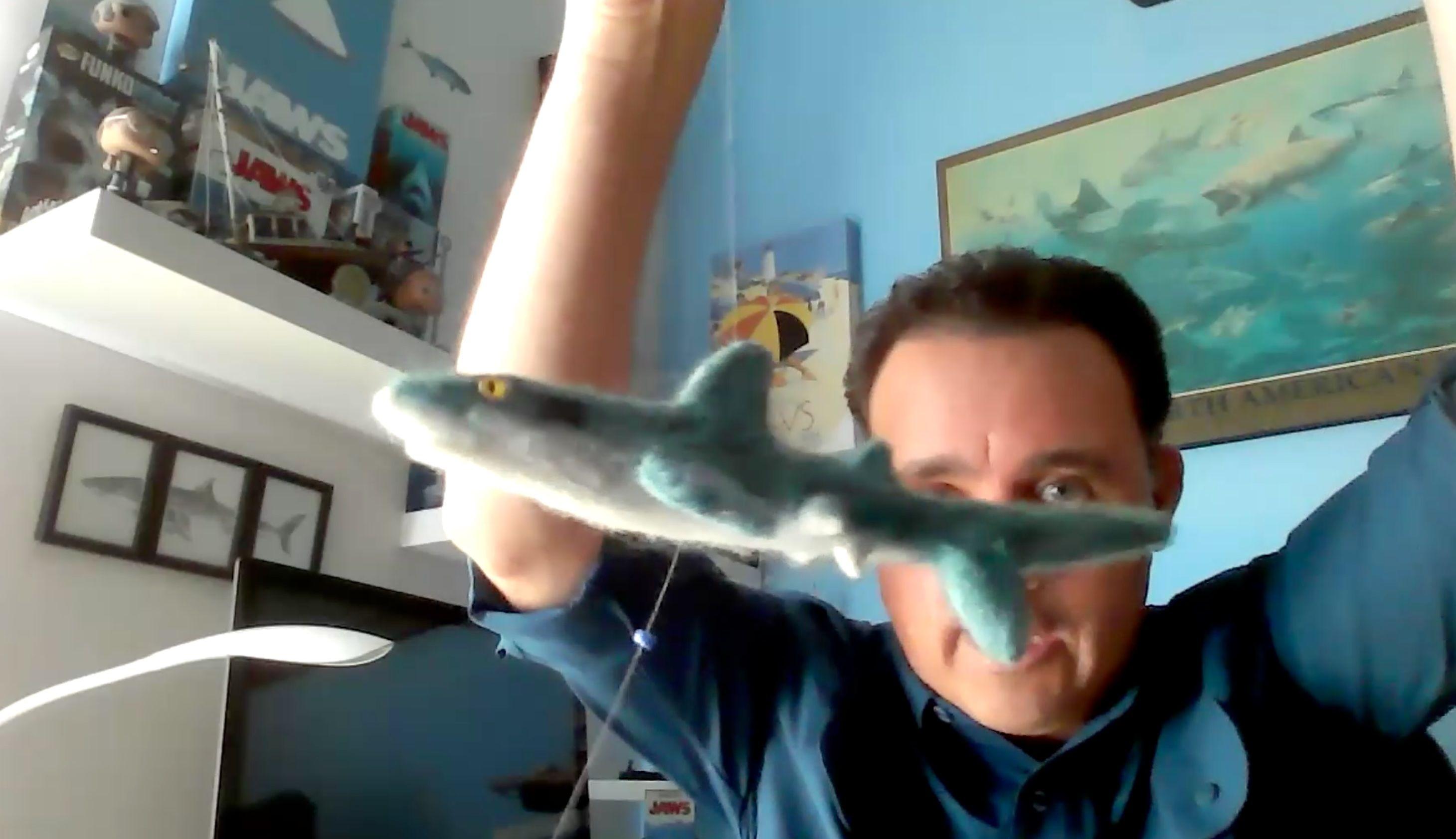 Hoyos sostiene un pequeño tiburón galápagos de juguete en las manos 